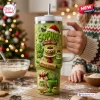 Hand holding a light green 40oz personalized tumbler with baking-themed holiday graphics and a straw in a festive kitchen.