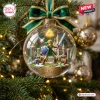 Clear glass ornament showing a miniature hero character with a sword and shield inside, hung on a pine tree branch.