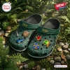 Top view of green clogs featuring character themed charms in a forest setting.