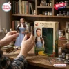 The Wizard of Oz 87th Anniversary Figure of Dorothy holding Toto next to the branded display box on a wooden desk.