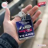 Close-up of a hand holding a square Transformers 40th anniversary keychain with a gradient background.