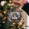 Close-up of a UFC Championship Octagon Christmas ornament held in hand against a blurred holiday tree.