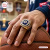USA Basketball FIBA 2026 World Champions ring featuring a large blue stone and gold band worn on a hand resting on a ball.