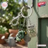 Closeup of Victa Mowers 75th Anniversary metal keychain hanging on a green wooden post.