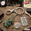 Closeup of Victa Mowers 75th Anniversary Metal Keychain with mower pendant on wood.