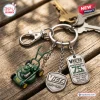 Closeup of Victa Mowers 75th Anniversary Metal Keychain resting on a wooden surface with keys attached.