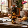 Front view of a Winnie the Pooh Halloween Pumpkin 40oz Stanley Tumbler with character designs on a wooden desk.