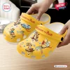 Closeup of Winnie the Pooh yellow clogs decorated with character charms.