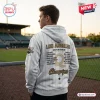 Back view of a man wearing the WPBL Los Angeles Queens 2026 Champions White Hoodie at a baseball stadium.