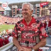 Man wearing a red Hawaiian shirt with Georgia Bulldogs themed text and stadium graphics at a football game.