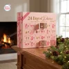 Front view of 24 Days Of Dance pink ballet advent calendar box on a wooden table with pinecones.