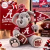 Front view of an Alabama Crimson Tide plush elephant toy wearing a red jersey and holding a miniature football and pennant flag.