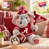 Front view of an Alabama Crimson Tide plush elephant toy holding a football and flag on a couch.