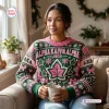 Front view of woman wearing a green and pink Alpha Kappa Alpha 1908 Ugly Christmas Sweater while holding a mug.