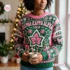 Front view of a person wearing an Alpha Kappa Alpha 1908 Ugly Christmas Sweater with pink and green holiday motifs.