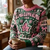 Front view of an Alpha Kappa Alpha 1908 Ugly Christmas Sweater featuring pink and green holiday motifs while holding a mug.