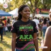 Front view of woman wearing a black Juneteenth Black History Month shirt with green and pink graphics.