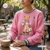 Front view of an Alpha Kappa Alpha Pink Bear Sweatshirt worn outdoors while holding a coffee cup.