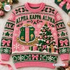 Front view of an Alpha Kappa Alpha Pink Ugly Christmas Sweater featuring a crest and holiday tree graphic.