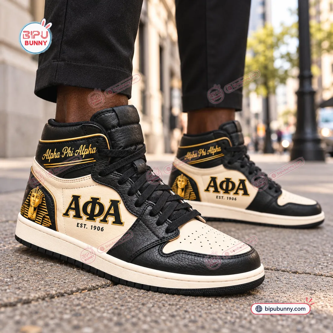 Close-up street view of the Alpha Phi Alpha Retro High Top Air Jordan 1 Sneakers worn with dark trousers showing the pebbled leather grain and Sphinx heel