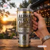 Hand holding an Alpha Phi Alpha Sphinx stainless steel tumbler with gold accents outdoors at sunset.