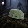 Side view of the olive green Anaheim Ducks x Jason Voorhees baseball cap resting on moss.