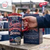 Hand holding Atlanta Braves 155th Anniversary 1871-2026 Tumbler next to matching box on wooden table outdoors.