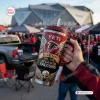Hand holding an Atlanta Falcons Rise Up 60th Anniversary Tumbler at a stadium tailgate.