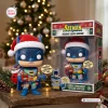 Front view of the Batman Holiday Lights Edition Vinyl Figure standing beside its packaging box with a Christmas tree background.