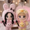 Close-up of two plush keychains wearing animal hoods, holding miniature lightsticks.