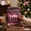 Front view of the Blackpink Mini Figures Advent Calendar with figurines displayed on a table near a Christmas tree.
