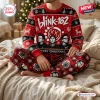 Front view of a person wearing a red Blink-182 Merry Christmas Ugly Sweater Jogger Set on a bed.