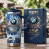 Front view of BMW 110th Anniversary 1916-2026 Handle Tumbler with matching gift box on wooden table.