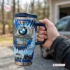Hand holding a blue tie-dye BMW 110th Anniversary handle tumbler with straw outdoors.