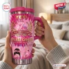 Front view of a pink tie-dye Breast Cancer 41st Anniversary 1985-2026 handle tumbler held in hands indoors.