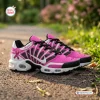 Side view of pink and white Breast Cancer Awareness Ribbon Air Max Plus Sneakers on a paved outdoor path.