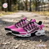 Side view of Breast Cancer Awareness Ribbon Air Max Plus Sneakers in pink and white on a gravel path.