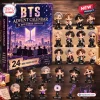 Front view of BTS Advent Calendar Figurine Set box displayed alongside multiple small character figurines.