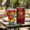 Hand holding a Buc-ees 44th Anniversary Tumbler Cup with tie-dye pattern and matching box on a wooden table.