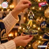 Closeup of hands hanging a California Golden Bears Kevin Moen Ornament on a lit Christmas tree.
