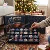 Hand opening a Chicago Cubs Christmas advent calendar filled with baseball themed ornaments near a decorated tree.