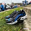 Side view of Detroit Lions Black Air Max Plus Sport Shoes resting on grass and concrete steps outdoors.