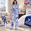 Front view of a model wearing a blue and white printed satin pajama set in a bedroom setting.