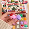 Closeup of a hand holding two small squishy toys in front of a Christmas Dumpling Squishy Toy Advent Calendar box.