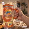 Hand holding an orange Fanta 86th Anniversary YETI handle tumbler with straw in a room.