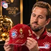 Closeup of a man holding an FC Bayern Munich red Harry Kane signed baseball cap.
