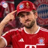 Close-up view of an FC Bayern Munich Red Harry Kane Signed Baseball Cap worn by a man in a red jersey.