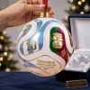 Hand holding a soccer ball Christmas ornament with number 10 and Trionda design near a velvet box.
