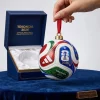 Hand holding a Trionda 2026 FIFA World Cup Christmas ornament in front of its blue box.