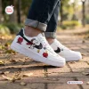 Side view of Flying Ace Snoopy Low-Top Air Force Sneakers worn with blue jeans on a brick walkway.